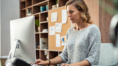 Indio A woman wearing a gray sweater, sitting in an office while using a computer