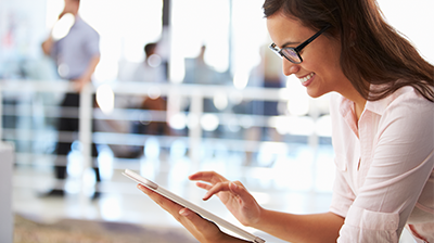 A woman working on her tablet smiling