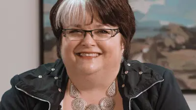 Woman smiling with large painting hanging on the wall of her office in the background.