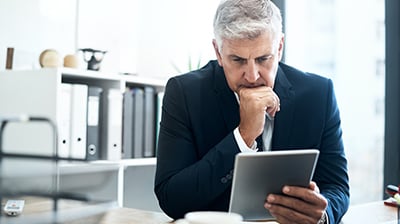 A focused businessman looking at a tablet in his hand