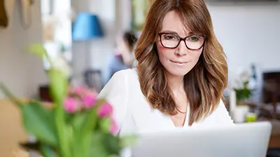 Woman dressed in business casual attire looking at laptop.